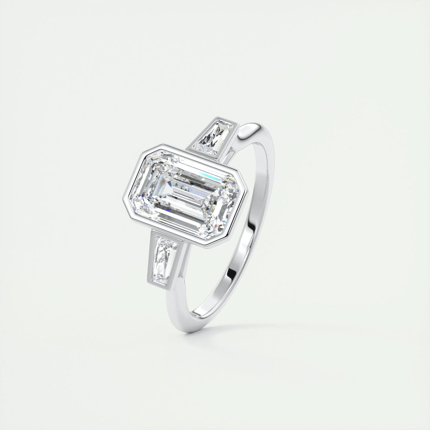 
                  
                    2.30 CT Emerald Cut Bezel 3 Stone Moissanite Engagement Ring 4
                  
                